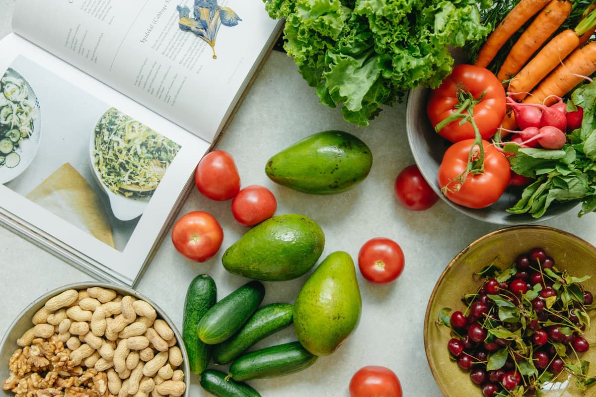 An open cookbook surrounded by fresh produce