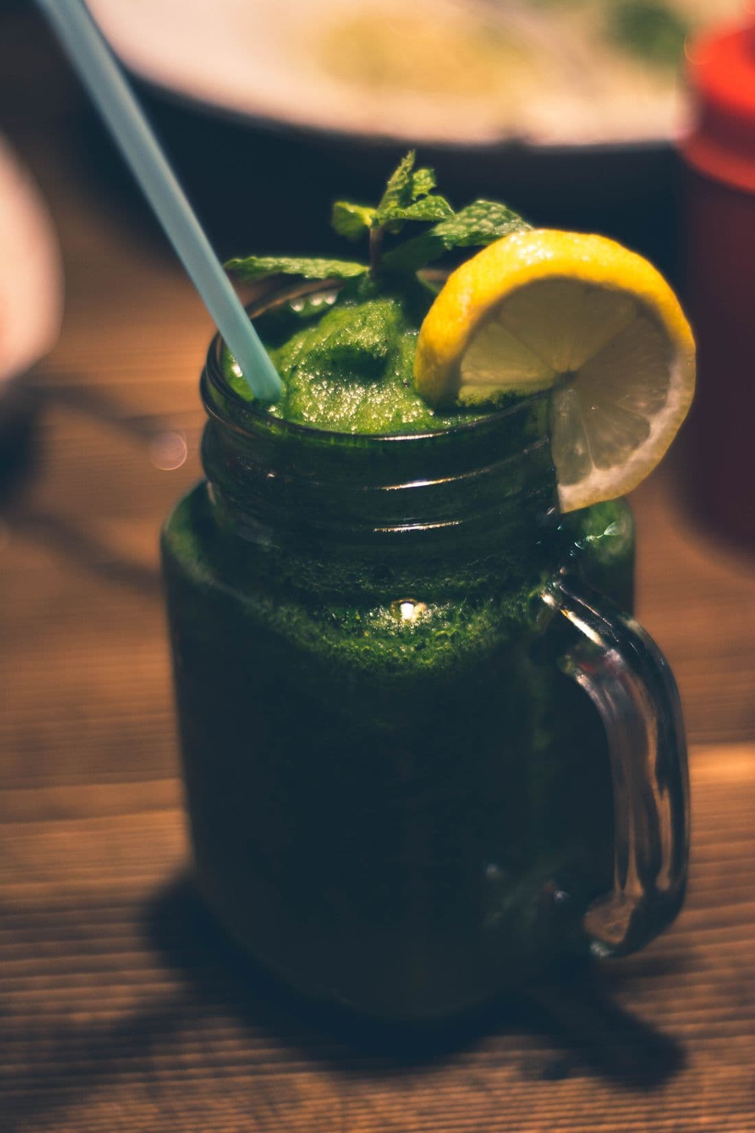 A bottled green smoothie beside fresh fruit